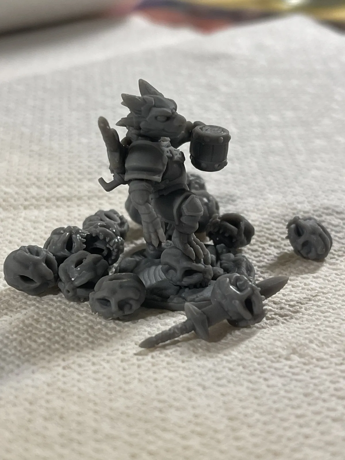 An angled view of Puck on a shop towel, with loose skulls and a spare sword from the calibration prints around him.