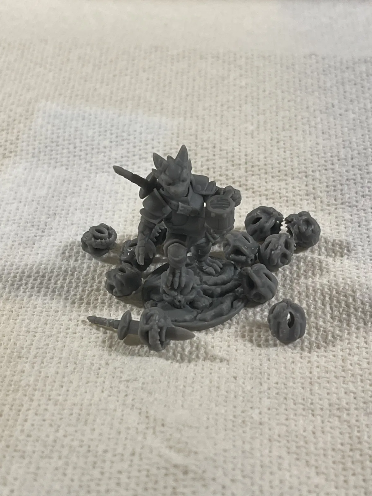 A top-down view of Puck on his round base, surrounded by the spare skulls, with a spare sword at lower left.