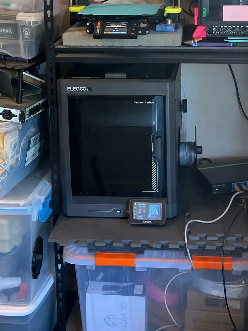 Closer view of Lucie, the Elegoo Centauri Carbon, on the bottom shelf, with its front door and control screen visible.